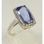 A TANZANITE AND DIAMOND DRESS RING, the cushion cut stone of approximately 5cts claw set to a border