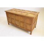 AN OAK PANELLED COFFER in the manner of Robert Thompson "Mouseman", hinged multi panelled lid over