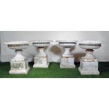 A SET OF FOUR VICTORIAN CAST IRON URNS of half fluted campana form with ovolu moulded rim, on fluted