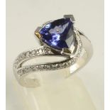 A TANZANITE AND DIAMOND DRESS RING, the triangular facet cut tanzanite claw set to open crossover