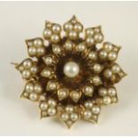 A VICTORIAN SEED PEARL FLOWERHEAD BROOCH, centred by a slightly larger pearl to a plain solid back