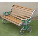 A VICTORIAN CAST IRON GARDEN BENCH of scroll back form with slatted hardwood seat and back, scrolled