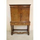 A WILLIAM & MARY WALNUT AND FEATHER BANDED CABINET ON STAND, the moulded cornice over cushion frieze