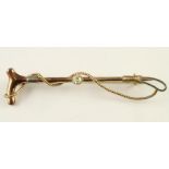 AN EDWARDIAN 15CT GOLD STICK PIN, in the form of a riding crop centred by a claw set brilliant cut