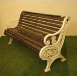 A CAST IRON PARK BENCH of scroll back form with slatted wood seat and back, scrolled arms, the