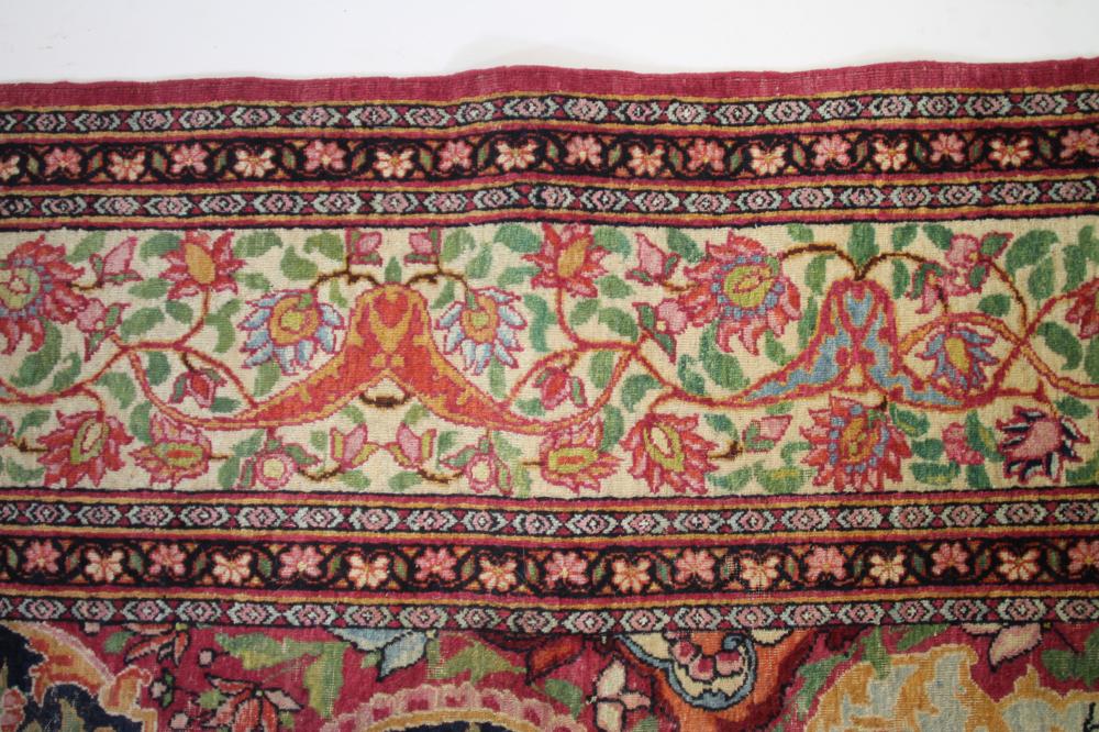A KERMAN RUG, the navy blue field with foliate scrolls centred by a raspberry flowerhead gul, - Image 6 of 6