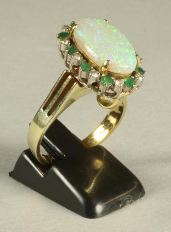 AN OPAL, EMERALD AND DIAMOND COCKTAIL RING/PENDANT, the oval cabochon polished opal claw set to an