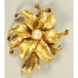 AN 18CT GOLD FLOWER BROOCH, the naturalistically engraved petals centred by a cultured pearl,