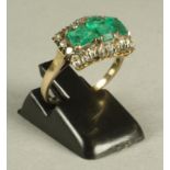 AN EMERALD AND DIAMOND RING, the central facet cut oblong emerald flanked by a pair of square cut