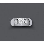 A THREE STONE DIAMOND RING, the central brilliant cut stone high claw set and flanked by two lower