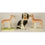 A VICTORIAN STAFFORDSHIRE POTTERY SPANIEL with black and white markings holding a basket of