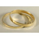 A PAIR OF 9CT GOLD PLANISHED BANGLES of plain form, 2 1/4" inner diameter, 30.8g total