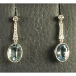 A PAIR OF AQUAMARINE PENDANT EARRINGS, the oval facet cut stones open back collet set hanging from