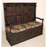 A VICTORIAN CARVED OAK PANELLED SETTLE, the back featuring urns and foliate scrolls, straight top