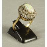 AN OPAL AND DIAMOND CLUSTER RING, the oval cabochon polished opal claw set to a border of fourteen