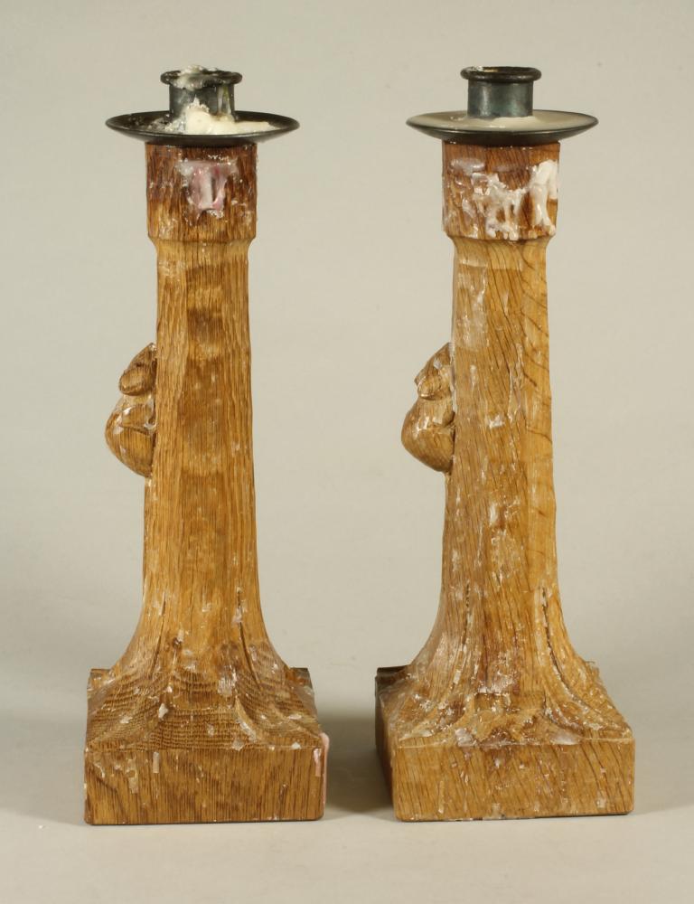 A PAIR OF ROBERT THOMPSON OAK CANDLESTICKS, the circular metal sconce on stepped faceted tapering