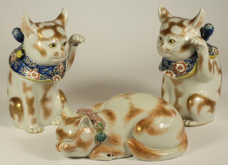 A PAIR OF JAPANESE PORCELAIN CATS, early 20th century, each with a raised left paw, wearing a