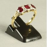 A BURMESE RUBY AND DIAMOND RING, the three oval facet cut rubies open back collet set in white