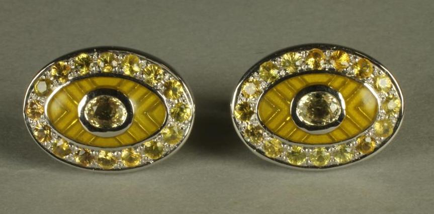 A PAIR OF YELLOW SAPPHIRE SET CUFFLINKS, the oval panels centred by a collet set stone on a yellow