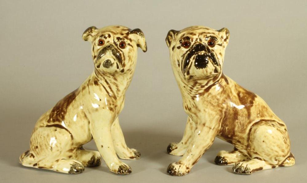 A MATCHED PAIR OF CONTINENTAL CREAMWARE SLIP CAST MODELS OF PUGS, c.1900, seated with free