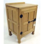 A ROBERT THOMPSON ADZED OAK BEDSIDE CABINET, of multi panelled oblong form, the moulded edged top