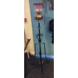 Wrought iron standard lamp with cranberry glass shade.