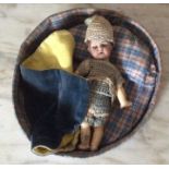 Small bisque headed doll in round bed