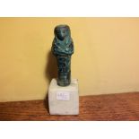 An Egyptian faience ushabti figure of a Pharoah 21st Dynasty 10cm high on a white marble stand