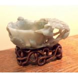 Fine quality Chinese carved jade libation cup on carved hardwood stand 16 cms wide