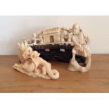 Three miniature ivory figures a dragon, a man and a landscape on a carved wooden stand