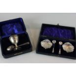 A silver christening egg cup and spoon in case and a pair of shell shaped silver salts with two