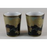 A pair of Japanese porcelain beakers with black and gilt decoration of grapevines, signature to