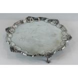 A circular silver presentation salver with raised scroll border and engraved name centre on three