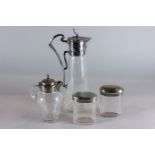 An Art Nouveau silver plate mounted glass claret jug, another jug and two oval dressing table jars