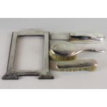 A silver photograph frame, a silver back hair brush and clothes brush, an ivory letter opener in