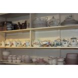 A large collection of crested and other souvenir china teapots and other crested ware