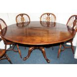 An oval oak dining table with burr walnut banded top on turned column and quadruple scroll legs,