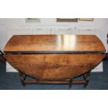 An 18th century oval oak gate leg table with two drop flaps and one end drawer, on turned legs