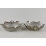 A pair of small Indian oval silver bowls with embossed bodies and bases with shaped raised sides