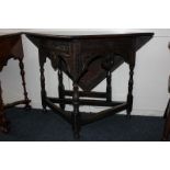 A 19th century oak corner table with folding front flap and carved frieze, on turned supports with