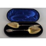 A pair of Victorian plated serving spoons with floral handles and shaped lobed bowls in case