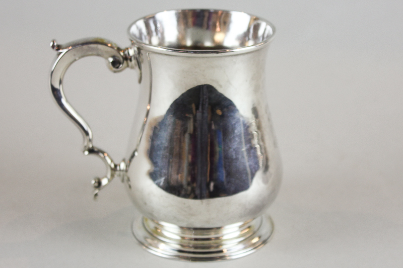 An early George III silver mug, maker I T London 1761, with scroll handle on circular base (
