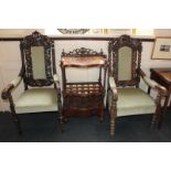 A pair of Victorian carved oak elbow chairs with 'crown' cresting and padded backs and seats, with