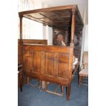 A 17th century style double size oak four poster bed with double arch and carved panelled foot board