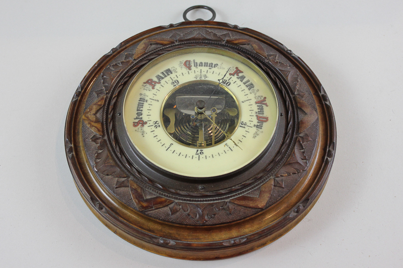 A Victorian aneroid barometer with scale 27 to 31 inches and marker and pointer, in carved