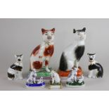 Two Staffordshire figures of cats seated on cushions (a/f), 18cm high, a pair of smaller seated cats