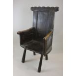 A 17th century oak chair with panelled arms and back with wooden seat on four rustic legs (NC)