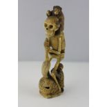 A 19th century Japanese carved ivory 'skeleton' with monkey on its shoulders and at its feet, 18cm