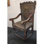 A 17th century carved oak wainscot chair with arched panel back and curved arms, on turned legs