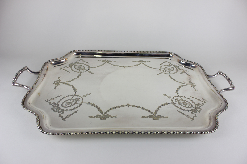 A rectangular plated two-handled tea tray with shaped raised edge and engraved ribbon and bell
